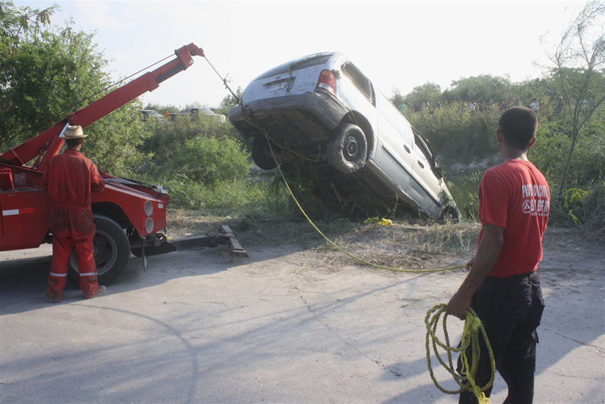 A FLOTE. La camioneta en que viajaban los futbolistas amateur es sacada del agua por una grúa.