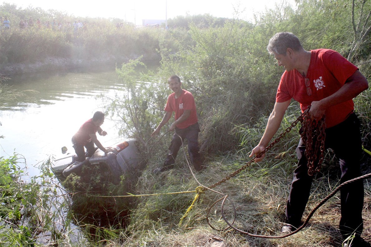 MANIOBRAS. Los bomberos realizan amarres con cadenas y cables de acero a un vehículo, para extraerlo del canal Rodhe, donde cayó con todo y tripulantes. 