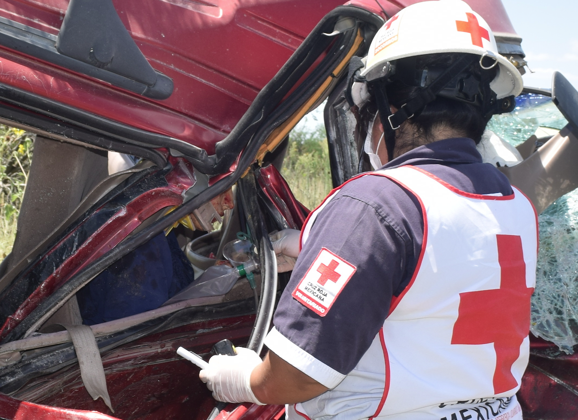 VÍCTIMA. Una paramédico de la Cruz Roja suministra oxígeno a la mujer, quien se observa prensada en la cabina de la camioneta.