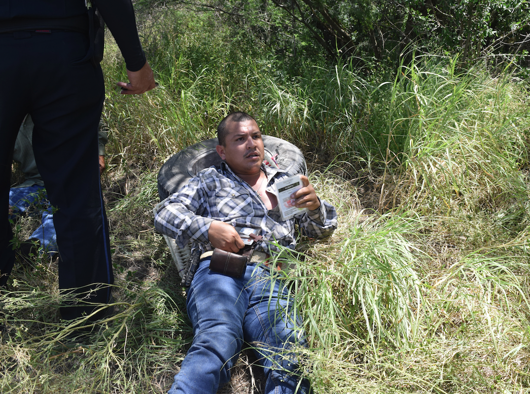 CONDUCTORES. Recostado sobre una llanta se observa al esposo de la víctima, y sentado entre el monte al presunto responsable del accidente.