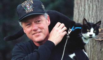 Bill Clinton deja que “Socks” se suba sobre su hombro tras su paseo matutino.