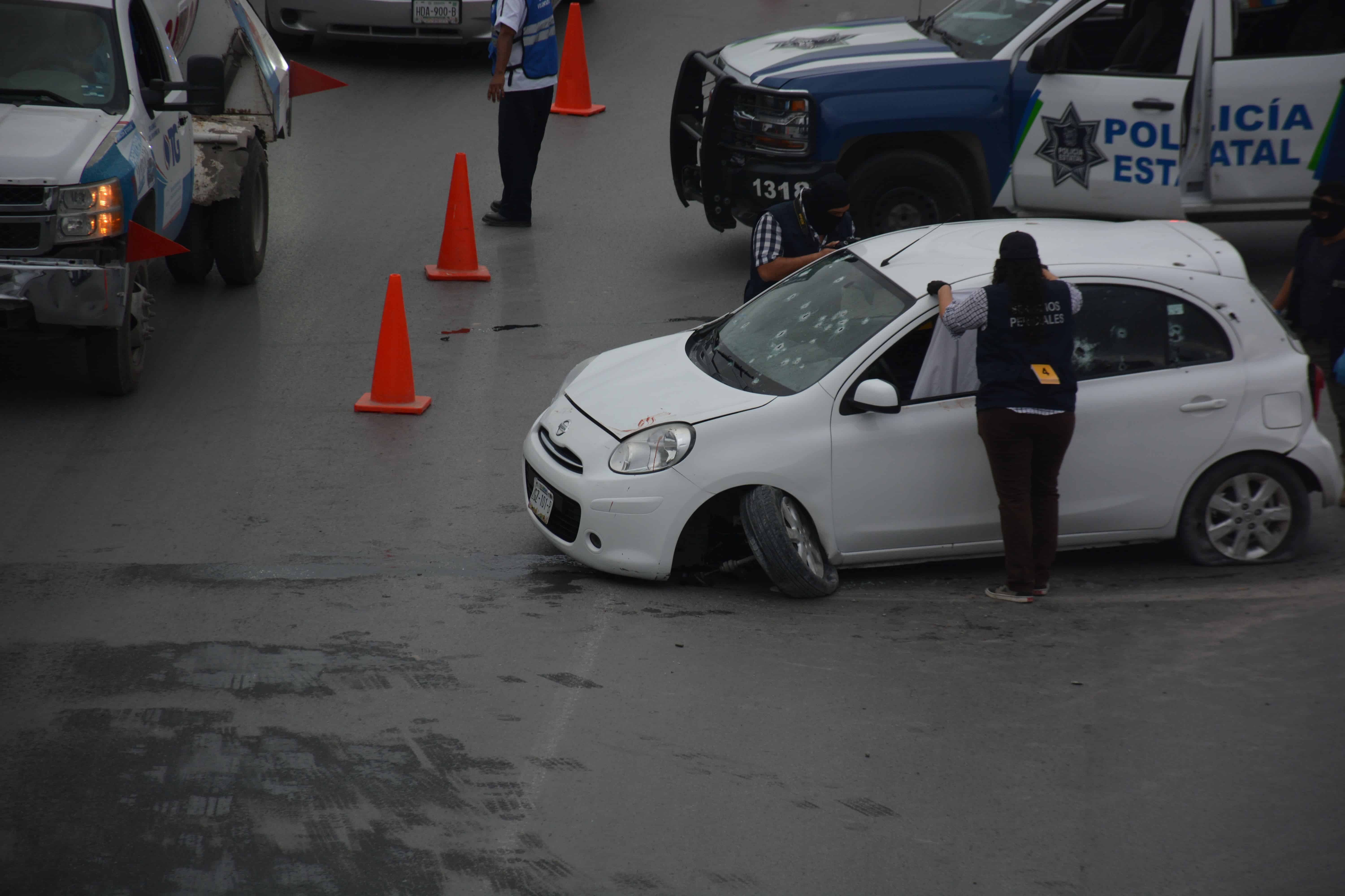 PARA EVITAR el morbo, una perito cubre la ventanilla donde se encontraba el cadáver del conductor.
