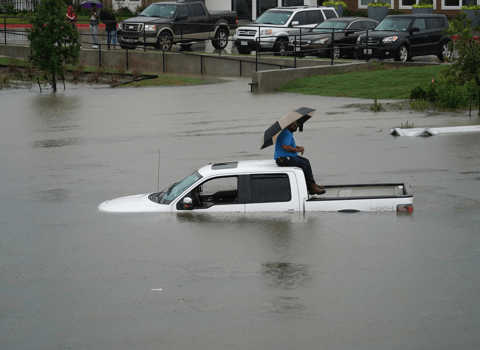 RESIGNADA. Una persona permanece arriba de su vehículo con su paraguas.