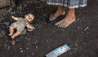 Felisa Lem Cal, de 68 años, en el exterior de su casa junto a una muñeca y una mascarilla abandonadas.