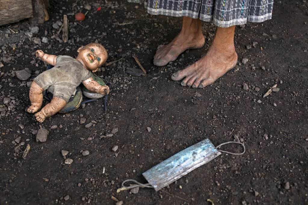 Felisa Lem Cal, de 68 años, en el exterior de su casa junto a una muñeca y una mascarilla abandonadas.