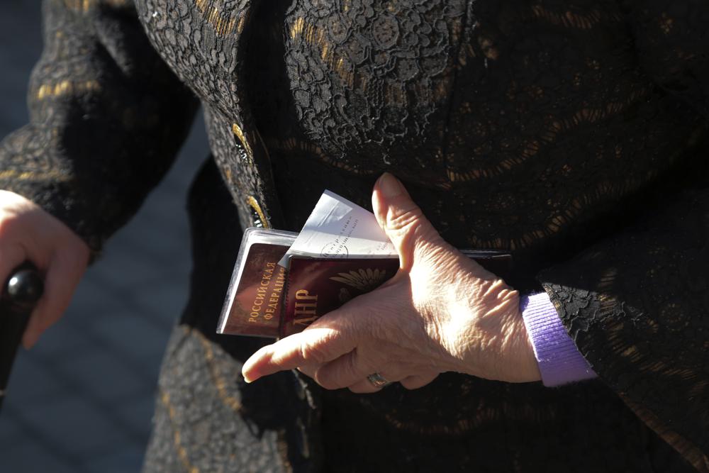 Una anciana sostiene sus pasaportes ruso, izquierdo y de la República Popular de Donetsk mientras espera ser evacuada a Rusia, en Donetsk, el territorio controlado por militantes prorrusos, en el este de Ucrania, el sábado 19 de febrero de 2022.