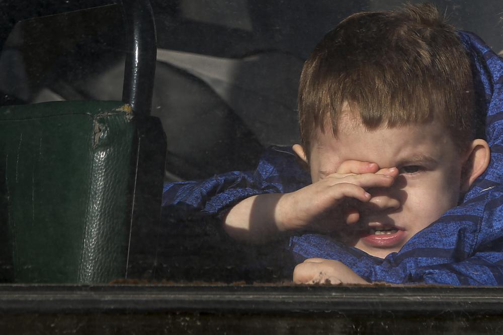 Un niño que espera ser evacuado a Rusia mira a través de la ventana de un autobús, en Donetsk, el territorio controlado por militantes prorrusos, en el este de Ucrania, el sábado 19 de febrero de 2022.