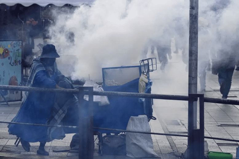 Una vendedora de palomitas de maíz empuja su carrito entre nubes de gases lacrimógenos lanzados por la policía durante enfrentamientos con educadores, que se manifestaban para reclamar salarios más altos y en contra del nuevo currículo de las escuelas púb