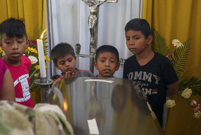 Vecinos asisten al velorio del migrante Francisco Rojche en su casa en Chicacao, Guatemala.