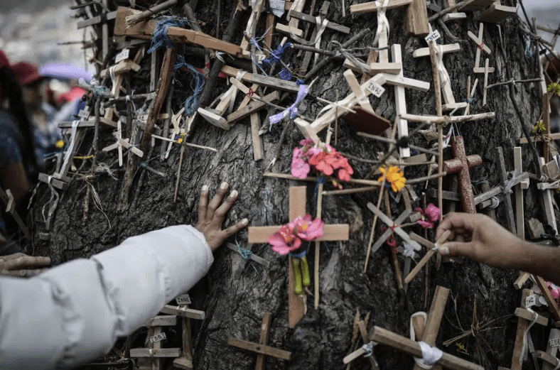 Fieles colocan cruces en el tronco del Árbol de la Vida durante una procesión de Viernes Santo, en las colinas del vecindario de Ciudad Bolívar.