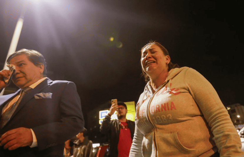 Personas lloran frente al hospital al que fue trasladado  del candidato presidencial Fernando Villavicencio después de su asesinato durante un mitin de campaña en Quito, Ecuador.