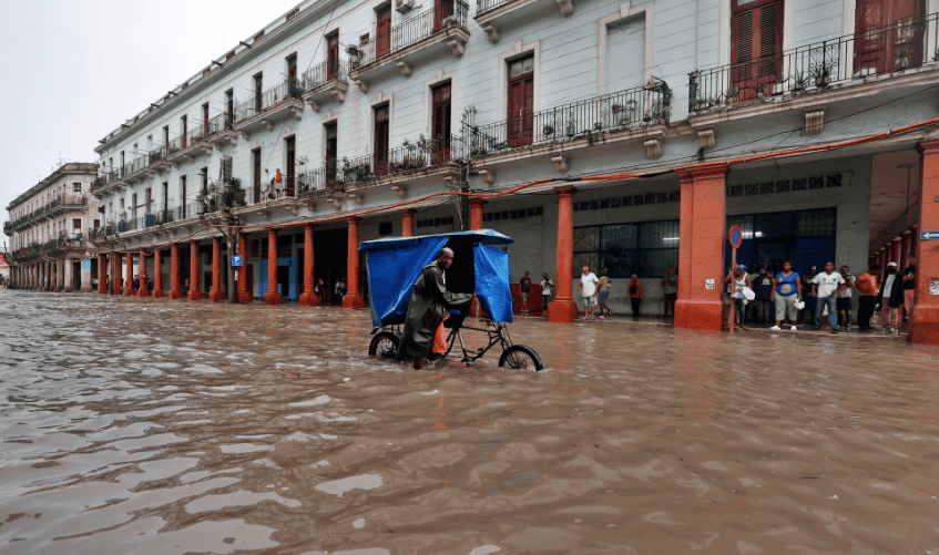 Un hombre empuja su bicitaxi por una calle inundada en La Habana.