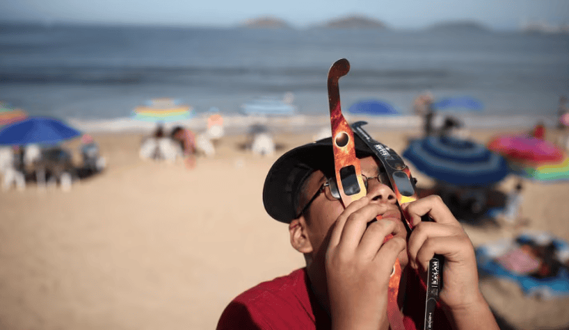 Un niño usa dos juegos de anteojos para ver el eclipse en Mazatlán.