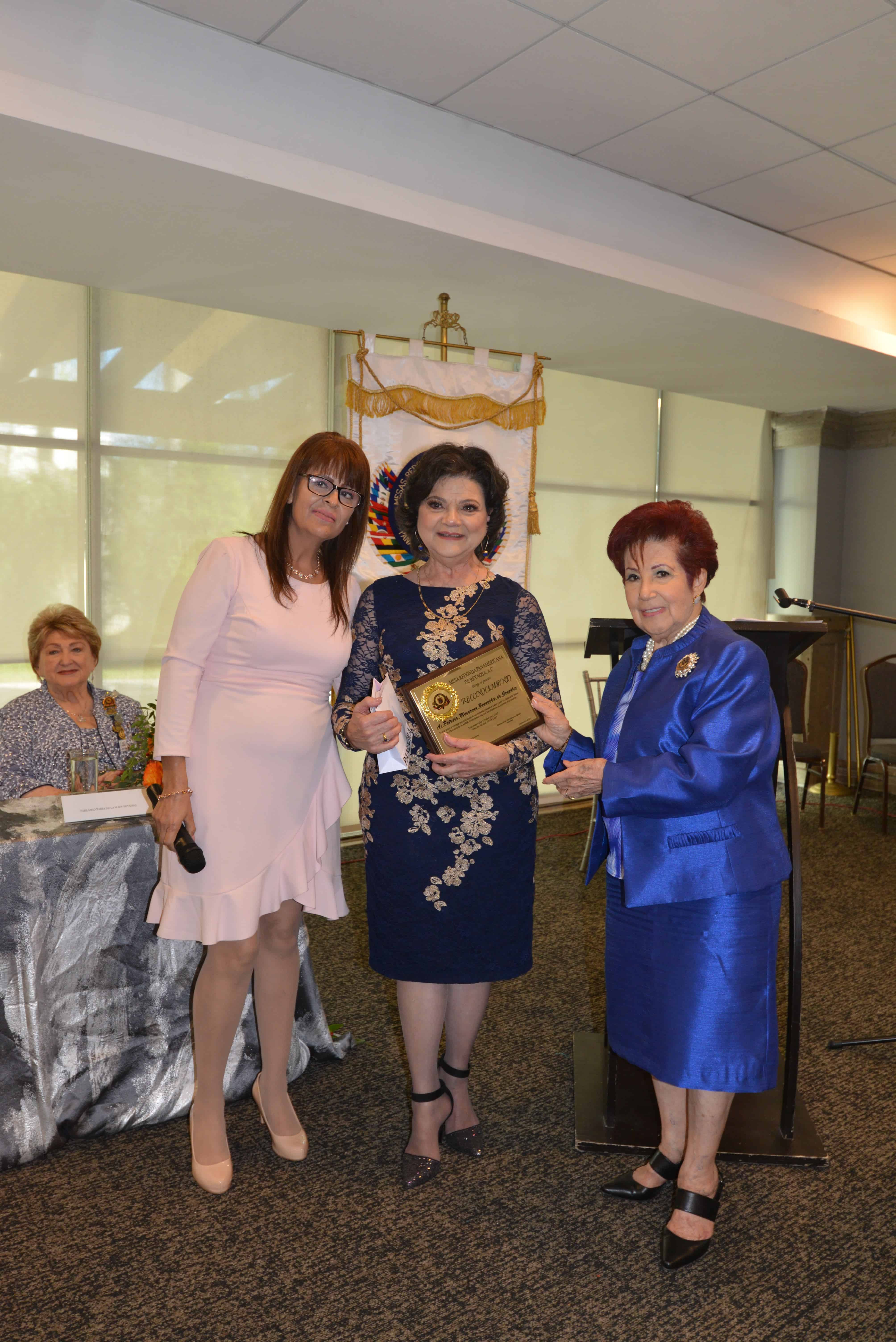 n  Macarena Benavides de González recibe reconocimiento por su año de trabajo, de manos de Abigail Barbosa y Aída de Cantú.