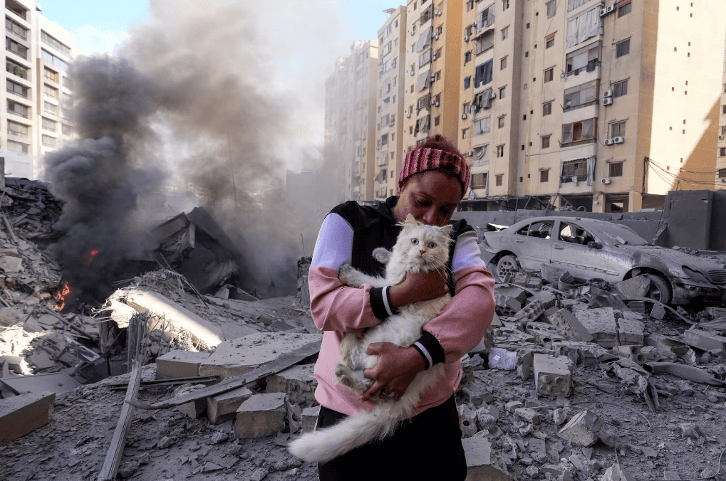 Una mujer sujeta a su gato junto a los escombros de un edificio colapsado tras un bombardeo israelí sobre Beirut, este miércoles.